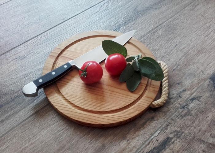 Küchenfliesen, Schneidbrett mit Messer, Tomaten und Salbei auf einer Küchenarbeitsplatte aus Fliesen in Holzoptik
